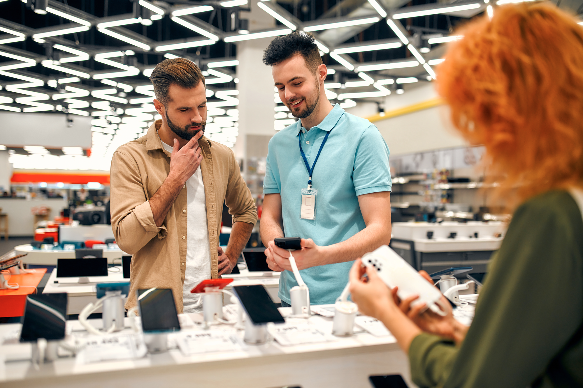 sales associate shows shopper a new smartphone in store